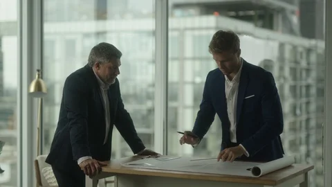 Two businessmen create blueprint in office with view on downtown LA Видео 127412730