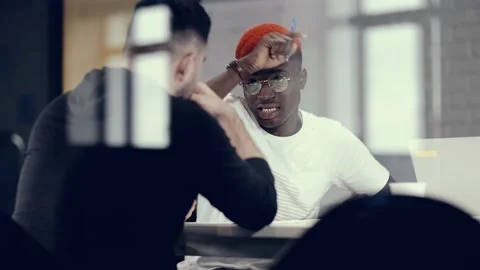 Two businessmen of different races work in the office discussing the success of Stock Footage 140918209