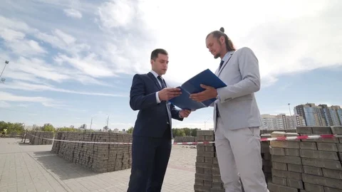 Two businessmen discuss plans for future construction Stock Footage 77664327