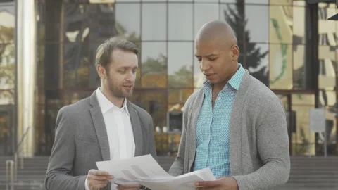 Two businessmen discussing documents outside a modern business building Stock Footage 311647630