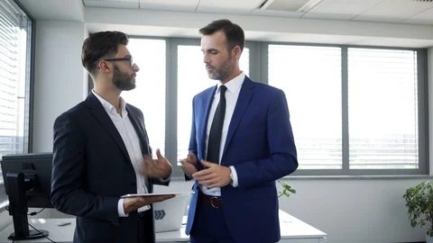 Two businessmen discussing work project and looking at tablet while standing Stock Footage 114813544