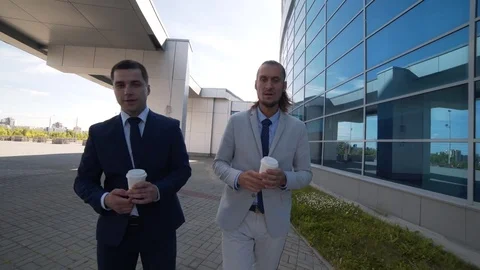 Two businessmen drinking coffee and taking a walk Stock Footage 77934795