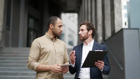 Two businessmen engaged in teamwork standing outside near office building.  Vidéo 338061566