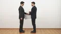 The two businessmen handshake and exchange suitcases on a white wall background 4k or 4k+ Resolution
