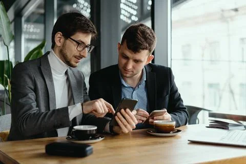 Two businessmen having a conversation using a smartphone Stock Photos