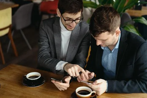 Two businessmen having a conversation using a smartphone Stock Photos