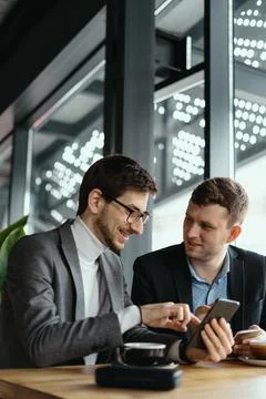 Two businessmen having a conversation using a smartphone Stock Photos
