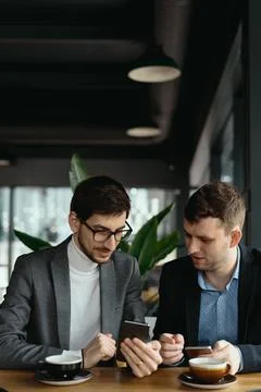 Two businessmen having a conversation using a smartphone Stock Photos