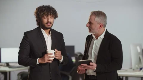 Two businessmen look at something on a digital tablet in the office. A middle Video stock 251561533