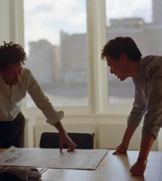 Two businessmen looking at document on board room table Stock Photos