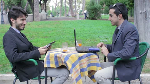 Two businessmen looking at tablet and laptop during business breakfast Stock Footage 32576343