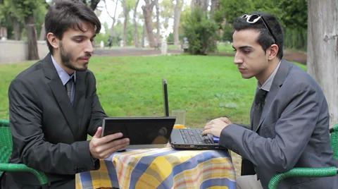 Two businessmen looking at tablet and laptop during business breakfast Video stock 32576935