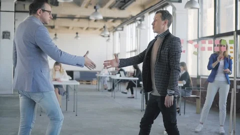 Two businessmen meet, shake hands, walk around the office, chat and discuss Stock Footage 108937865