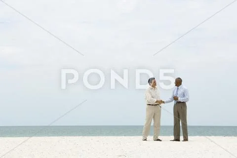 Two Businessmen Shaking Hands On The Beach