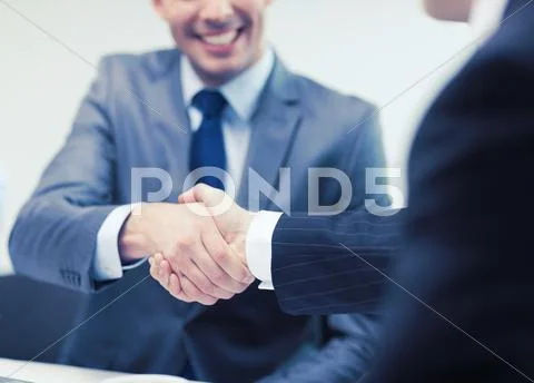 Two businessmen shaking hands in office Stock Photos