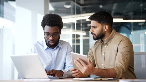 Two businessmen sitting at office desk communicating while using laptop  Stock Footage 329052502