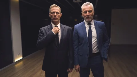 The two businessmen in suits posing on camera indoor. slow motion Stock Footage 124440651