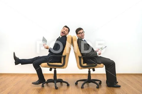 The two businessmen with a tablet and papers sit on the white wall background Stock Photos