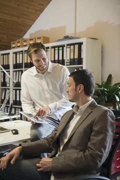 Two businessmen using digital tablet in an office and smiling, Bavaria, Germany 스톡 사진