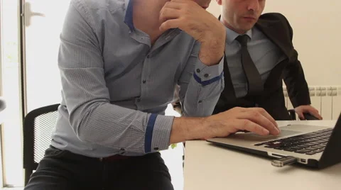 Two businessmen using laptop in office Stock Footage 62530296