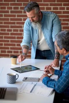 Two businessmen using tablet computer discussing financial graph data on mobile Foto stock