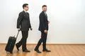 The two businessmen walking with a bag on the white wall background Photo