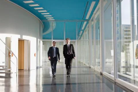 Two businessmen walking in the foyer of a convention center Stock Photos