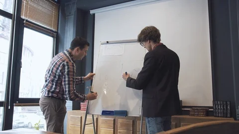 Two businessmen write on a flipchart Stock Footage 86489906