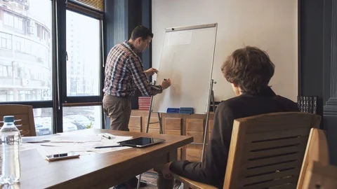 Two businessmen write on a flipchart Stock Footage 86489935