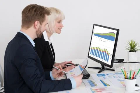 Two Businesspeople Analyzing Graph On Computer In Office Stock Photos
