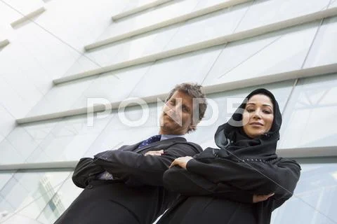 Two businesspeople standing outdoors by building smiling (high key/selective Stock Photos