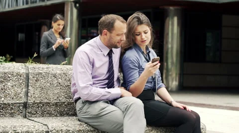 Two businesspeople talking and using smartphone sitting in city  HD Stock Footage 45545848