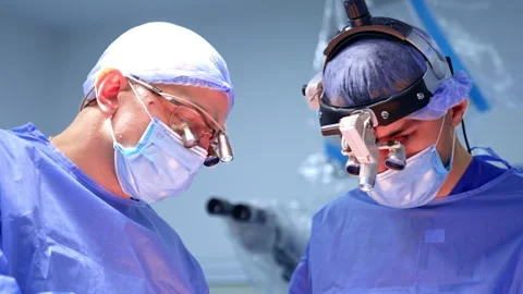 Two busy male surgeons working at operation. Portraits of the doctors performing Stockbeeldmateriaal 333337035