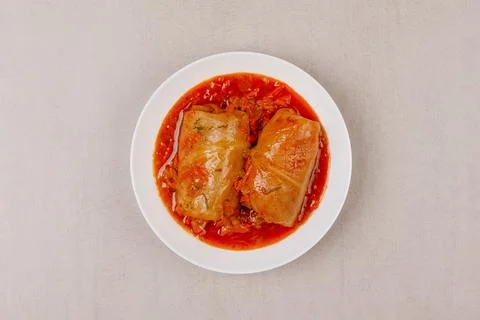 Two cabbage rolls stuffed with minced meat in vegetable gravy on a white plat Stock Photos