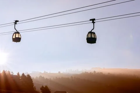 Two cable car cabins in the air and rising sun over Seiser Alm plateau covere Stock Photos