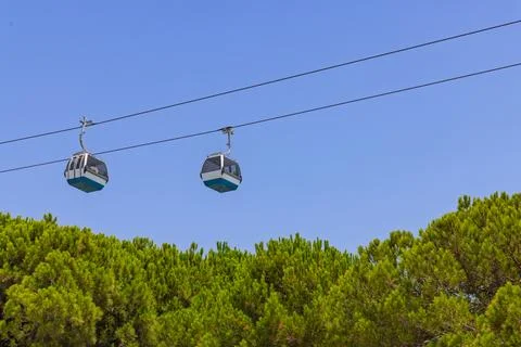 Two cable car cabins float against a clear blue sky, with the lush green foli Foto stock