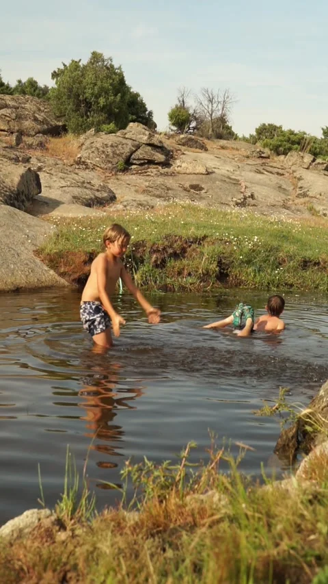 Two caicasico children bathing in a river in summer and one of them splashi.. Stock Footage 277453977