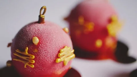 Two cakes with red mirror glaze and chocolate Christmas ornament stand on a Vidéo 83541356