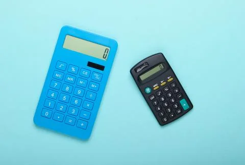 Two calculators on blue background. Top view. Stock Photos