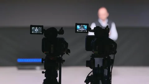 Two cameras on tripods capture a speaker during a studio present Stock Footage 323133850