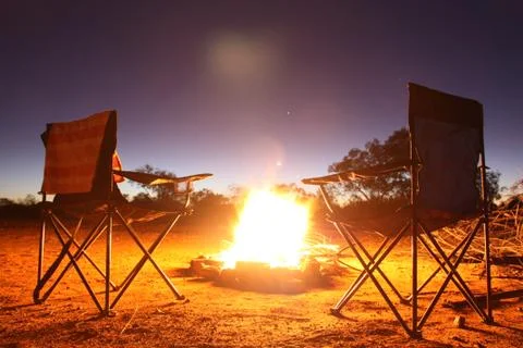 Two camping chairs in front of a camp fire Stock Photos