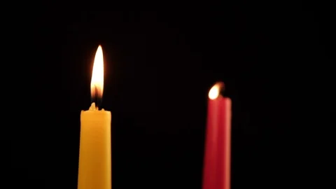 Two candles are burning red and yellow one of which is calm, and the other is Stock Footage 120088967