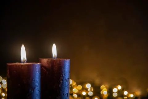 Two candles on black background with blurred Christmas lights Stock Photos