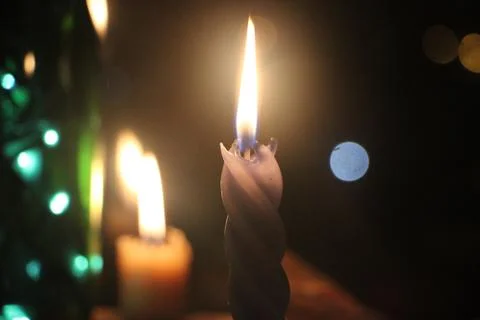 Two Candles burning in the dark with double fire and bokeh lights Photos