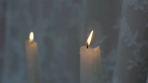 Two candles burning in the night closeup on a background of white cloth Stock Footage