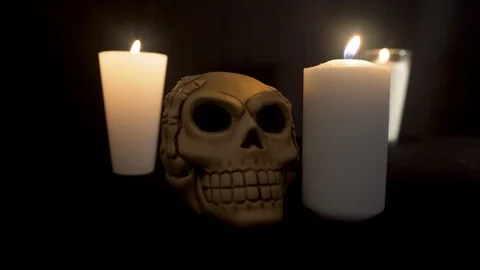 Two candles light off with a skull on the center of the candles Stock Footage 96687964