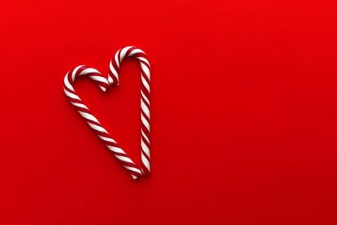 Two candy canes making a heart on a red background. Stock Photos