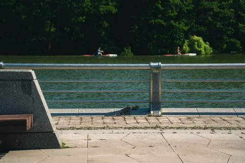 Two canoeists are sailing along the river. Embankment, steel fence Stock Photos