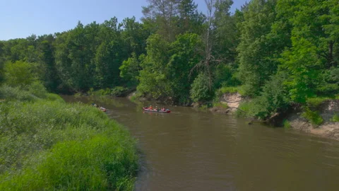 Two canoes with tourists float down the river, competing in speed. Kayakers on Stock Footage 233601547
