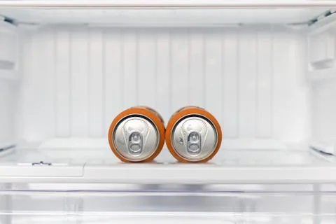 Two cans of beer lie in an empty fridge. Stock Photos